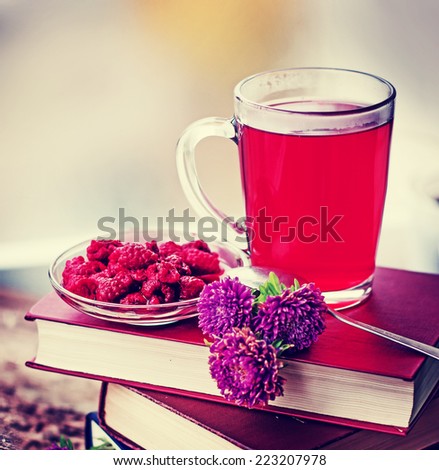 Raspberry jam tea/Romantic Autumn background with raspberry hot drink ( fruit tea) , flowers and books.