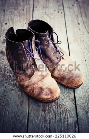 Old dirty cowboy boots/ Old and dirty military bootson wooden background