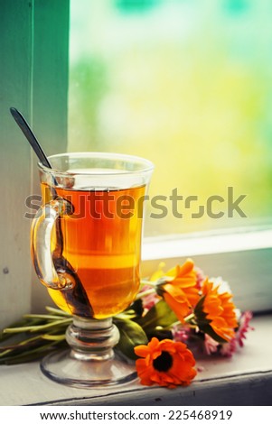 romantic autumn vintage background with books and tea/cup of  herbal tea with  flowers over window