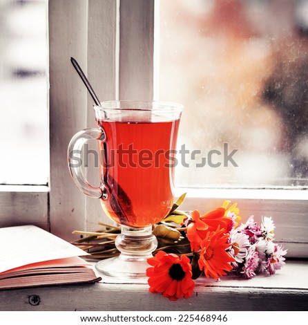 romantic autumn vintage background with books and tea/cup of  herbal tea with  flowers over window