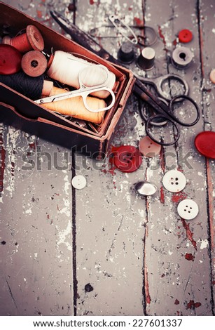Vintage Background with sewing tools and colored tape/Sewing kit. Scissors, bobbins with thread and needles on the old wooden background