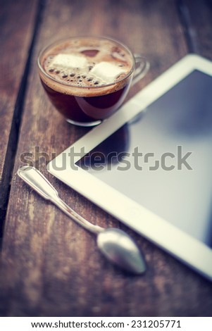 blank tablet device over a wooden workspace table and cup of coffee/ selective focus