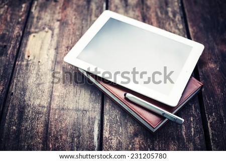 blank tablet device over a wooden workspace table/ selective focus