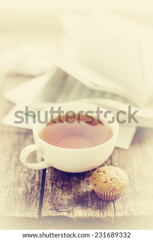 Digital tablet with note paper and cup of tea on old wooden desk. Simple workspace or coffee break in morning/ selective focus