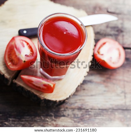 Glass of tomato juice on wooden table, on wood plants background, fresh drink/ selective focus