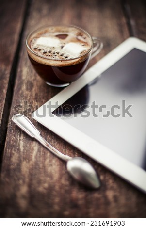 Cup of coffee with digital tablet computer on wooden table/ Break on the work place