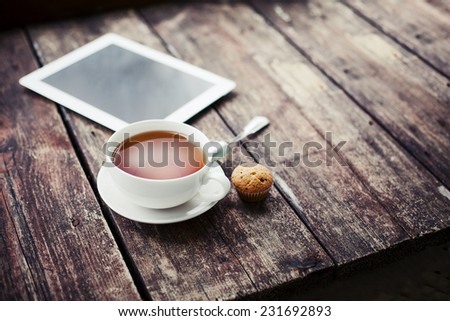 Digital tablet computer  on wooden table with cup of tea