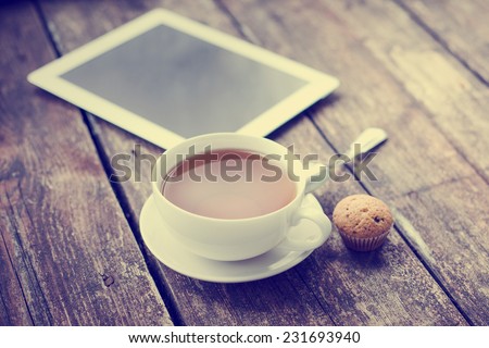 Digital tablet computer  on wooden table with cup of tea