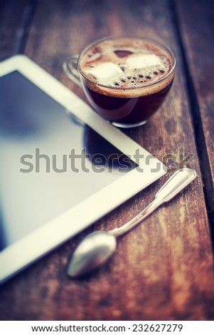 Cup of tea with digital tablet computer on wooden table with