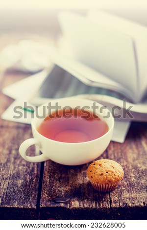 Digital tablet with note paper and cup of tea on old wooden desk. Simple workspace or coffee break in morning/ selective focus