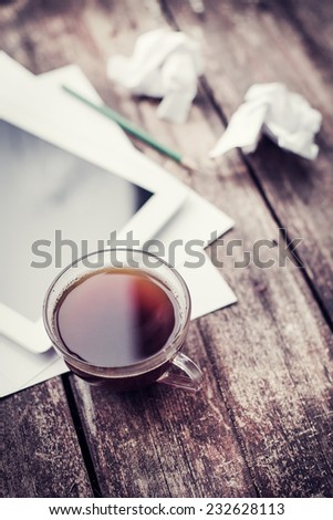 Cup of tea with digital tablet computer on wooden table