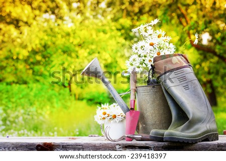 Outdoor gardening tools and flowers/ Spring Gardening tools and a straw hat on beautiful garden background