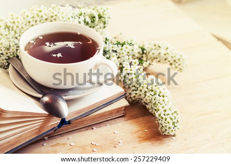 Books, flowers and cup of tea on wooden table