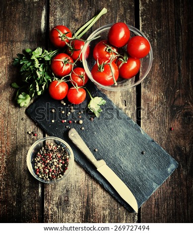 Fresh grape tomatoes with  pepper for use as cooking ingredients on wooden background