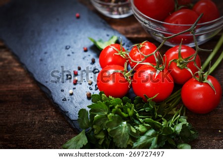 Fresh grape tomatoes with parsley and pepper for use as cooking ingredients on wooden background