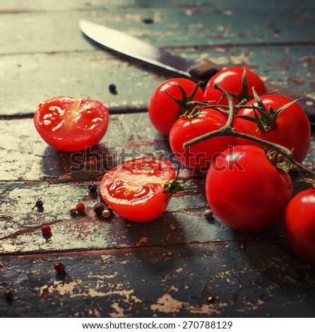 Fresh grape tomatoes with pepper for use as cooking ingredients on wooden background