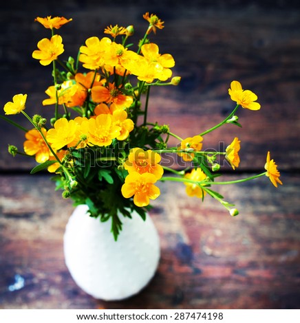 Wild flowers in a vase, bouquet of yellow flowers on wooden table
