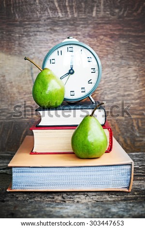 Alarm clock, book stack and pears. Schoolchild and student studies accessories. Back to school concept.