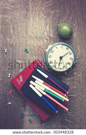 Alarm clock, book stack and felt pens. Schoolchild and student studies accessories. Back to school concept