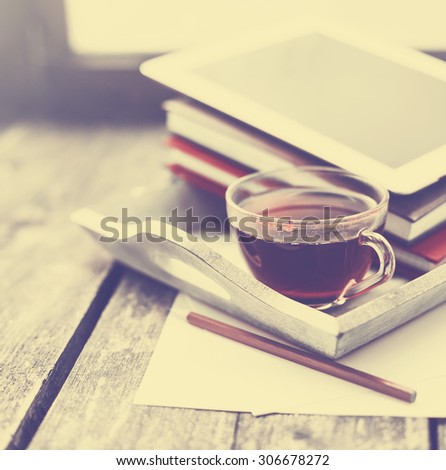 Digital tablet and cup of coffee on old wooden desk. Simple workspace or coffee break in morning/ selective focus