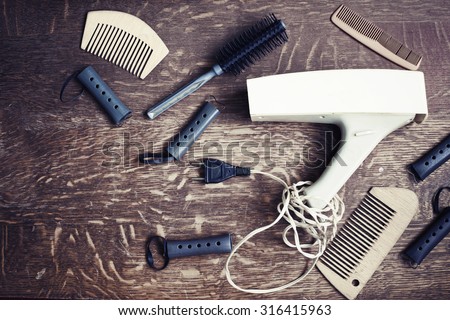 Vintage beauty set with hairdresser accessories -hair dryers, hair curlers,hairbrushes/ Hairdressing tools on wooden table close-up/ Retro concept