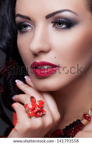 Close-up portrait of beautiful brunette with beauty spot wearing red lily ring