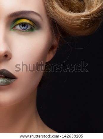 Half face closeup portrait of beautiful blond girl with yellow and green makeup