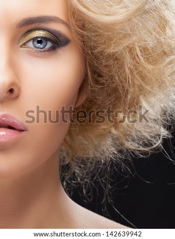 Half face closeup portrait of beautiful blond girl with golden eyeshadows and fluffy hair