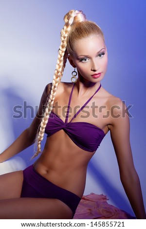 Beautiful blond girl in purple bikini looking like doll