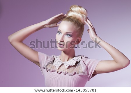 Portrait of beautiful blond girl in pink dress looking like doll over pink background
