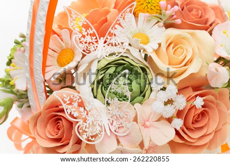 Wedding bouquet of artificial flowers in peachy, orange colours with lace butterflies on it