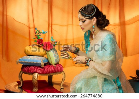Beautiful young woman dressed in oriental style taking piece of wedding cake