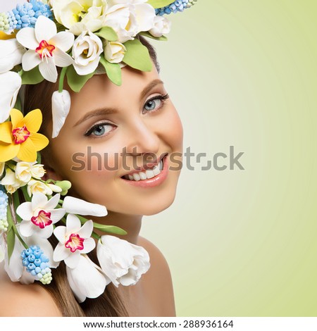 Closeup portrait of beautiful young happy woman with many flowers on head. Isolated over green background. Copy space, Square composition.