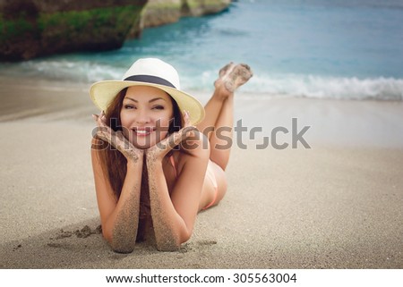 Beautiful young woman in biniki lying on sand near water. Outdoor shot. Tenerife.