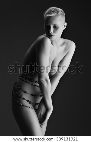 Beautiful young naked woman with beads on waist over dark background