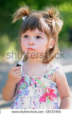 A little girl using lip gloss