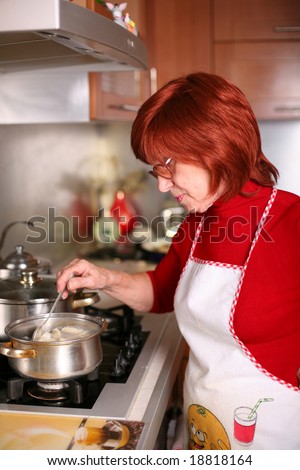 A middle aged woman stands in the kitchen cooking traditional Russian dish, pelmeni