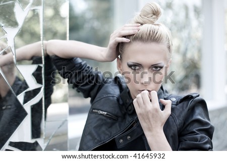 Stylish woman with dark makeup near the broken mirror