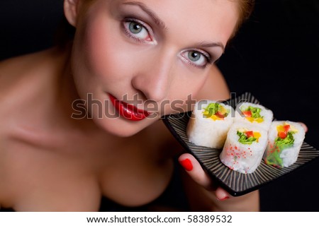 Pretty woman is holding a plate with japanese food over black background