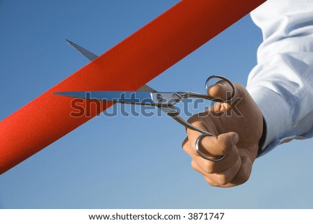 Red ribbon cutting with a pair of scissors for the inauguration of the new business activity