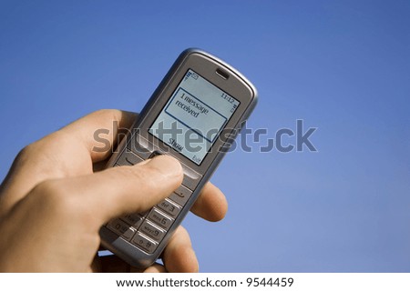 Message SMS received with mobile phone in the hand over blue sky