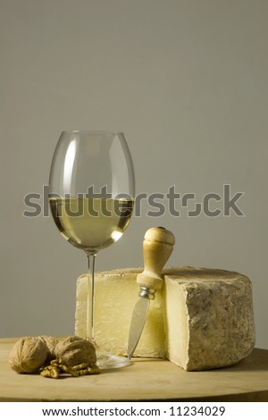Cutting board with genuine Italian food. White wine glass, ripe hard cheese from ewe\'s milk and walnuts. Space for text