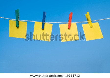 Four different post it hanging out with colorful pegs in a sunny day. Write it on whatever you want!