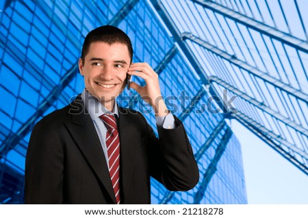 Portrait of young confident businessman talking on mobile phone outside the office