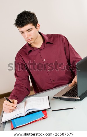 Young busy man studying and working on his laptop with note pad.