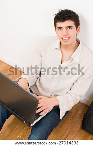 Happy young man working on his laptop with casual clothing