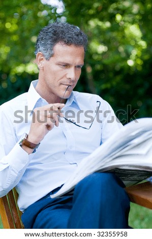 stock photo Handsome mature man reading news outdoor during a break