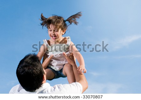 Father throw in air his little daughter in a clear blue sky with copy space for your text