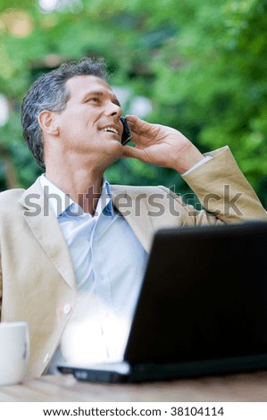 Smiling relaxed businessman talking on mobile outdoor