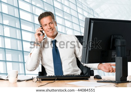 stock-photo-successful-businessman-sit-at-his-desk-while-talking-on-mobile-in-office-44084551.jpg